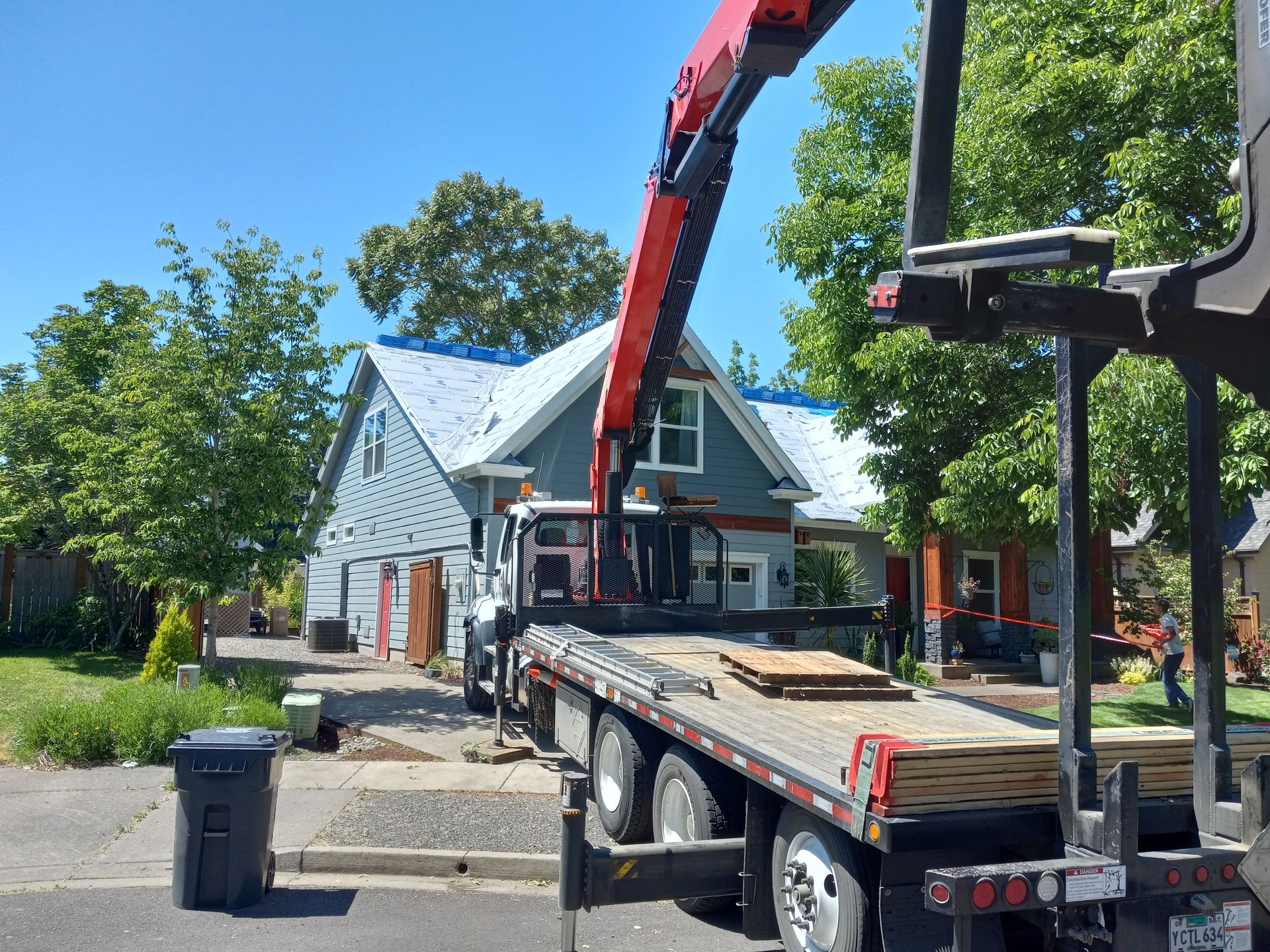 Bucket truck lifting debris from a house roof on a sunny residential street