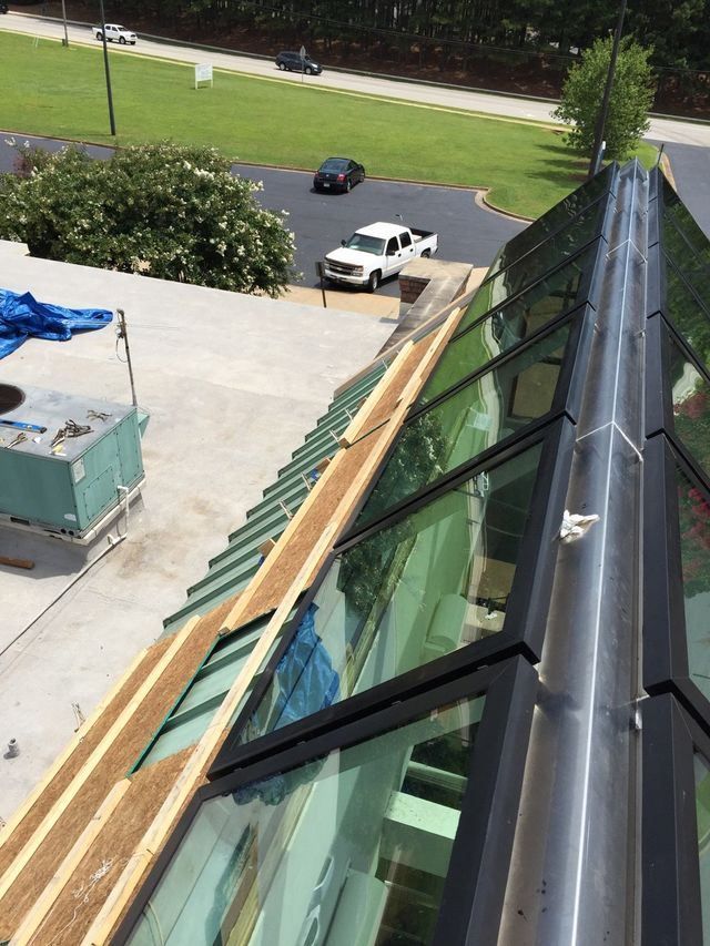 View from a rooftop, showing construction on a glass-walled structure with a truck below.