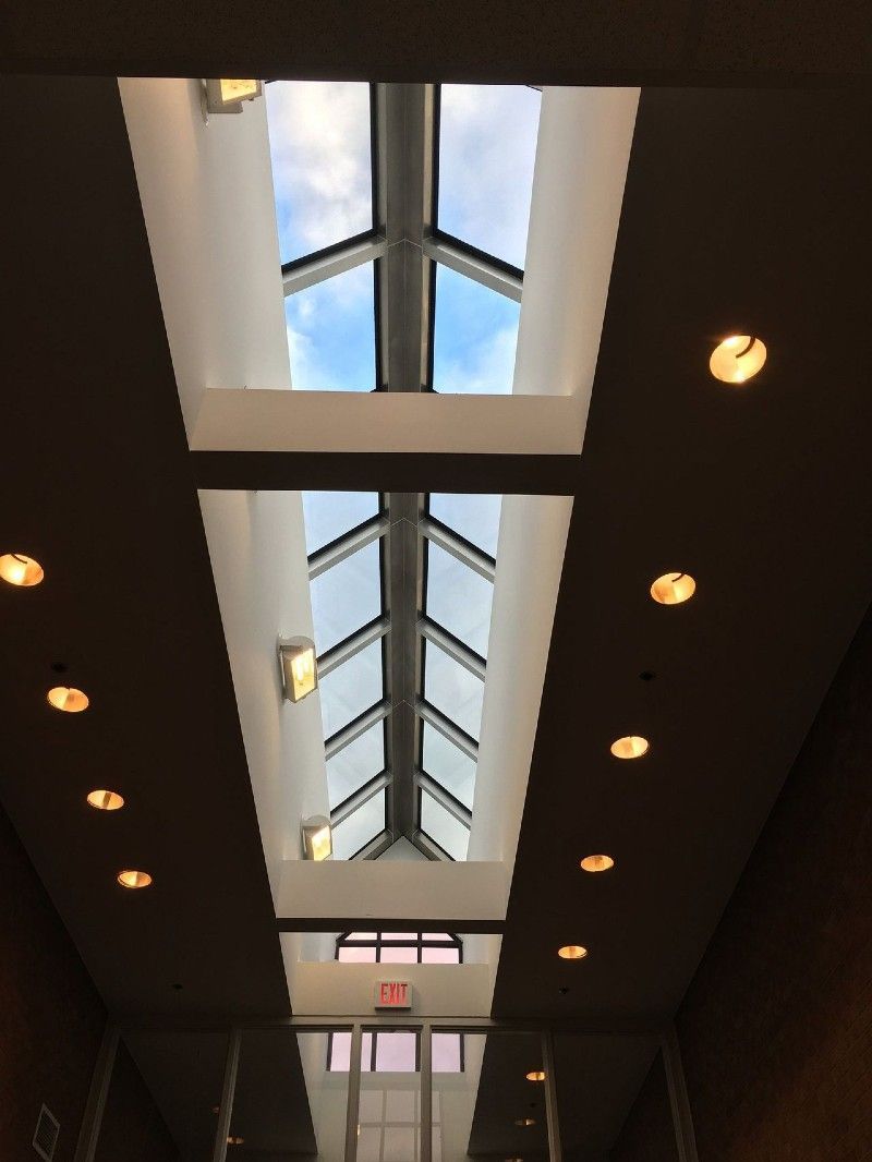 Interior hallway with a skylight, showing a blue sky, recessed lighting, and an exit sign.