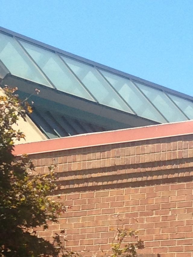 Brick building with glass roof angled to the sky. Sunny day.