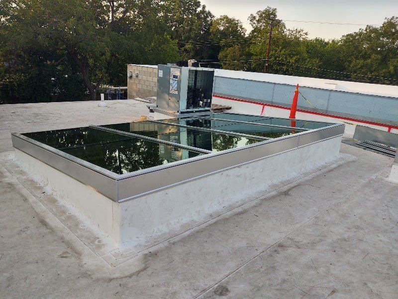 Skylight on a white rooftop, reflecting trees. Includes HVAC unit.