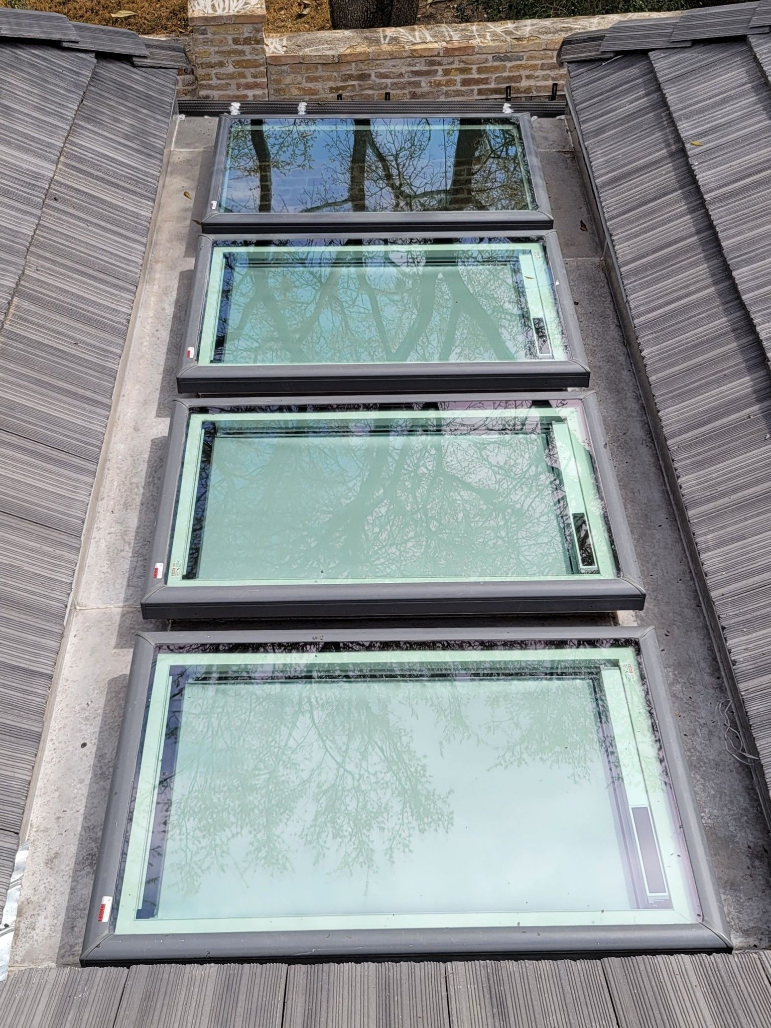 Four rectangular skylights installed in a gray shingled roof.