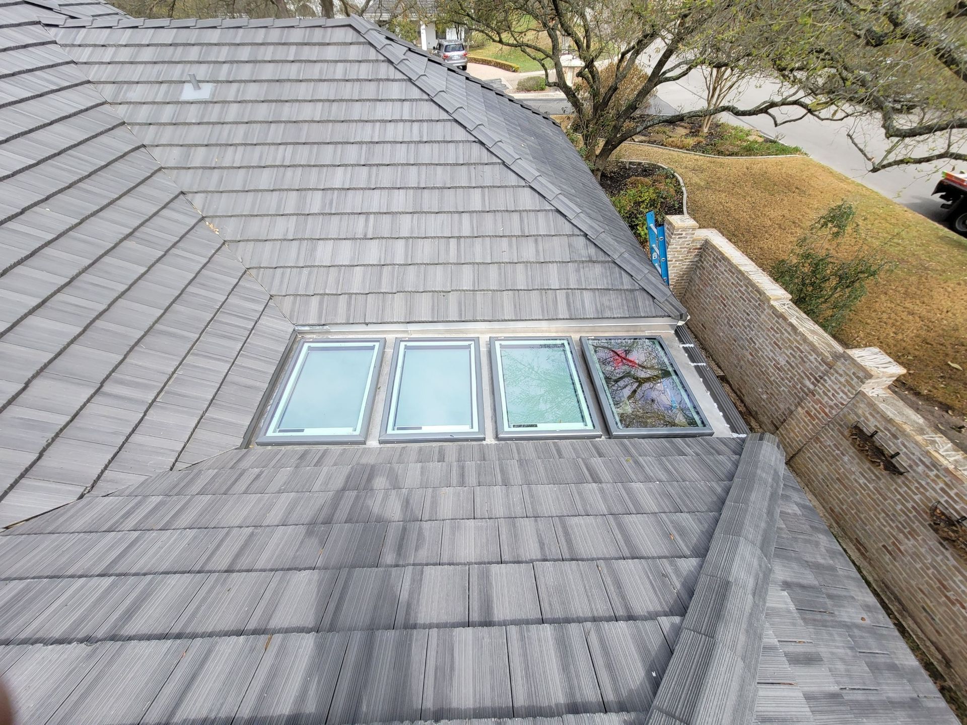 View of a gray roof with four windows. One window has a stained glass design.