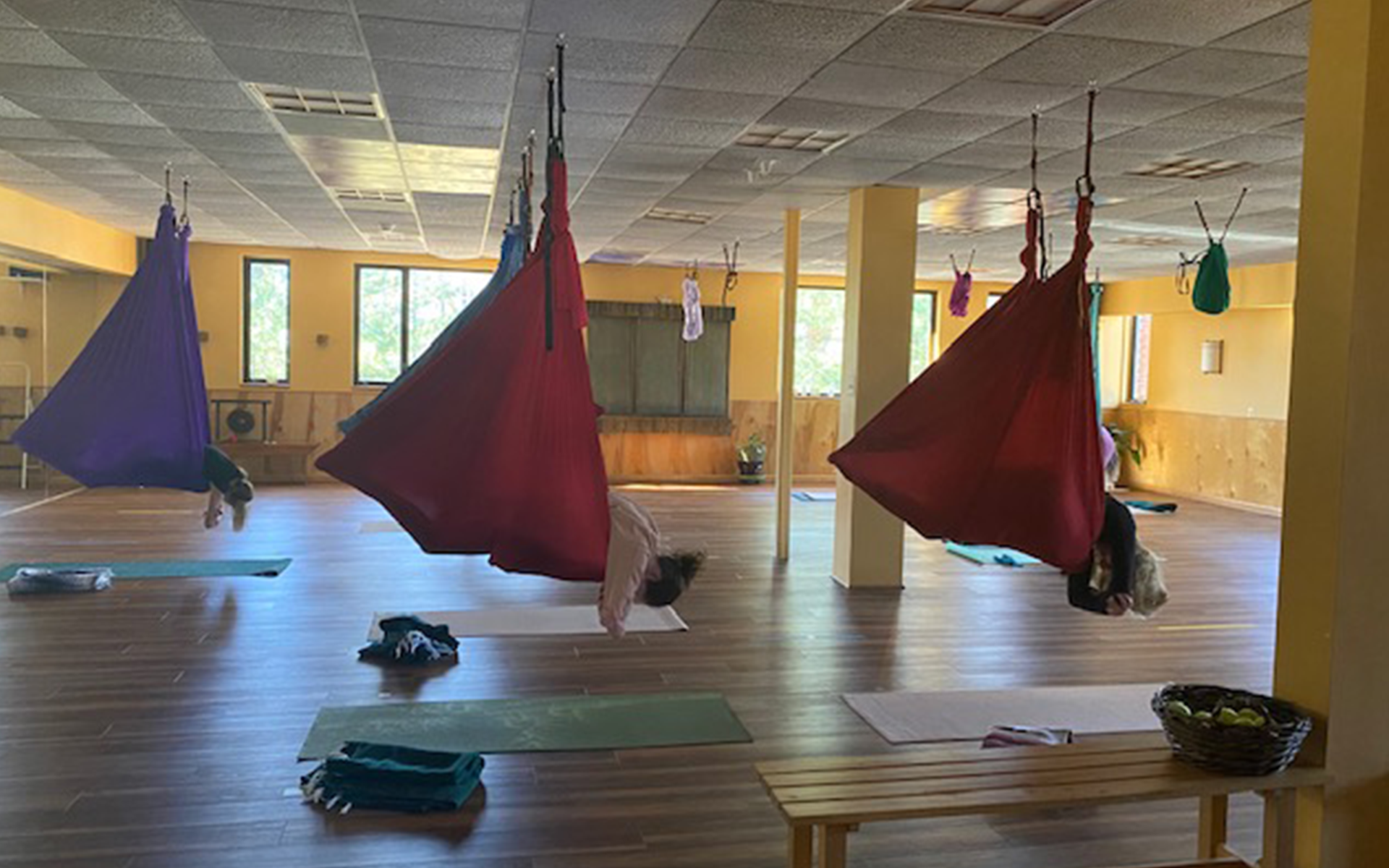 A group of people are doing aerial yoga in a gym.