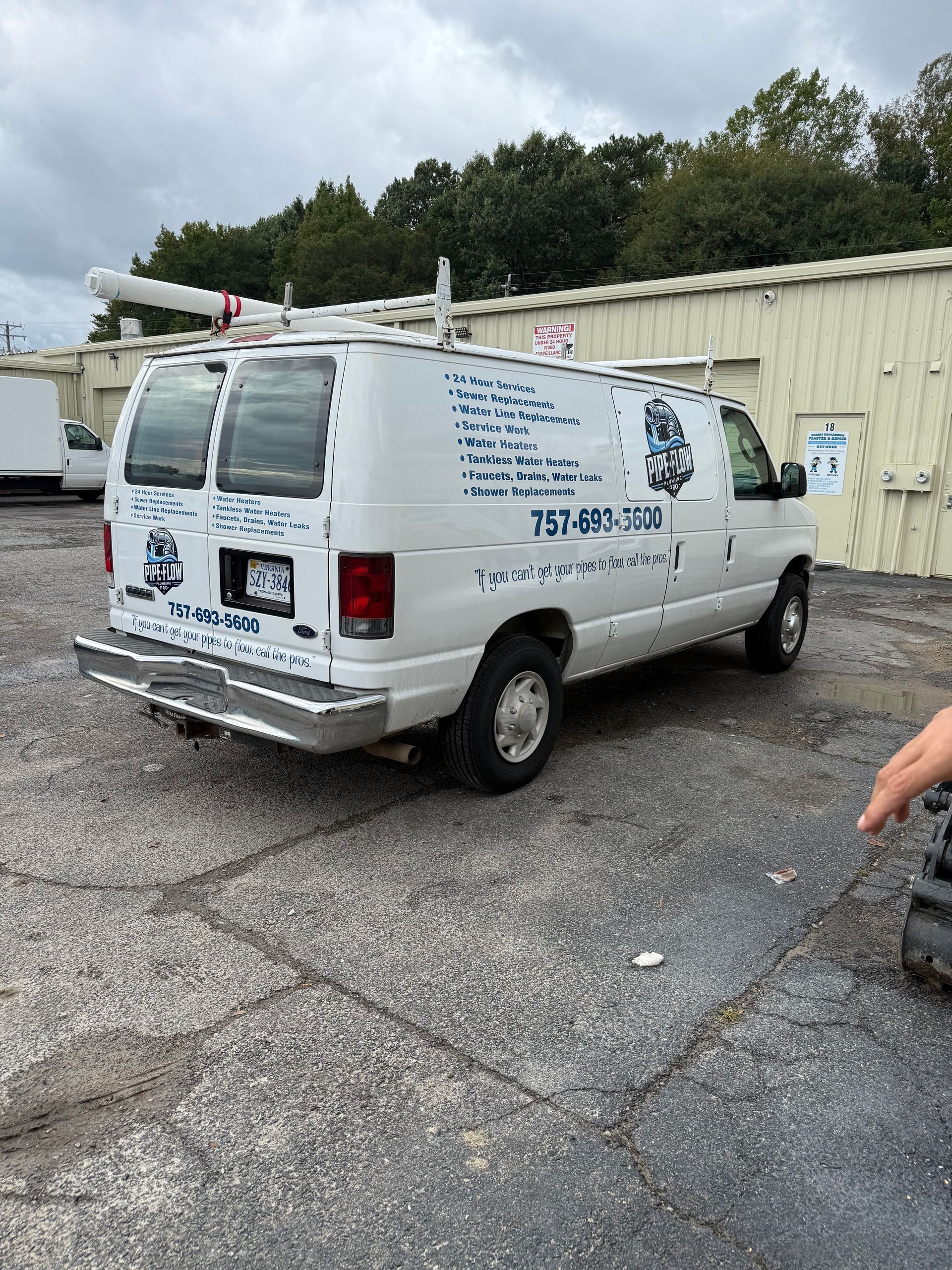 White service van parked in front of a building. It has a ladder rack and text on the side.