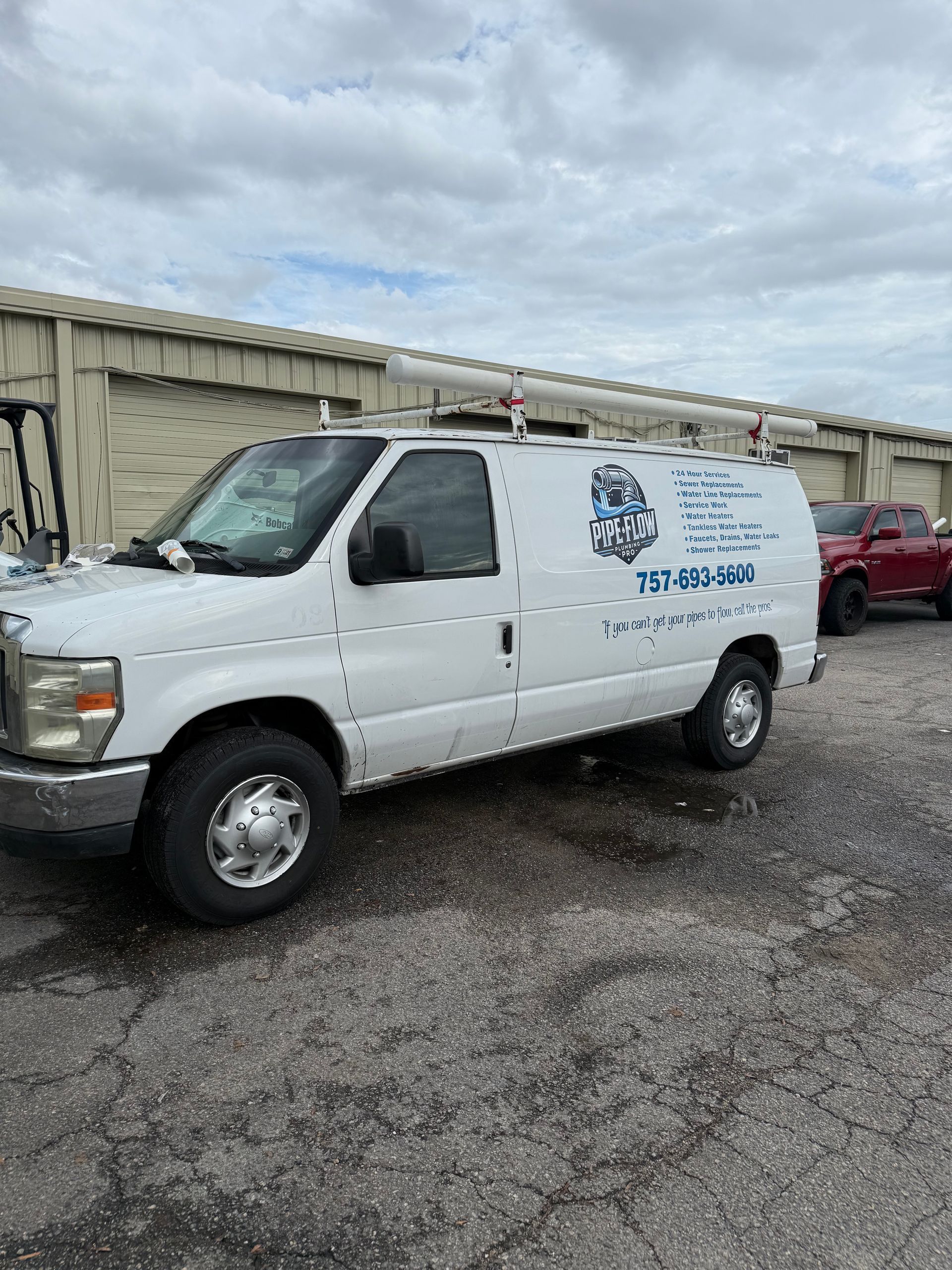 White service van with company logo parked near storage units on a cloudy day.