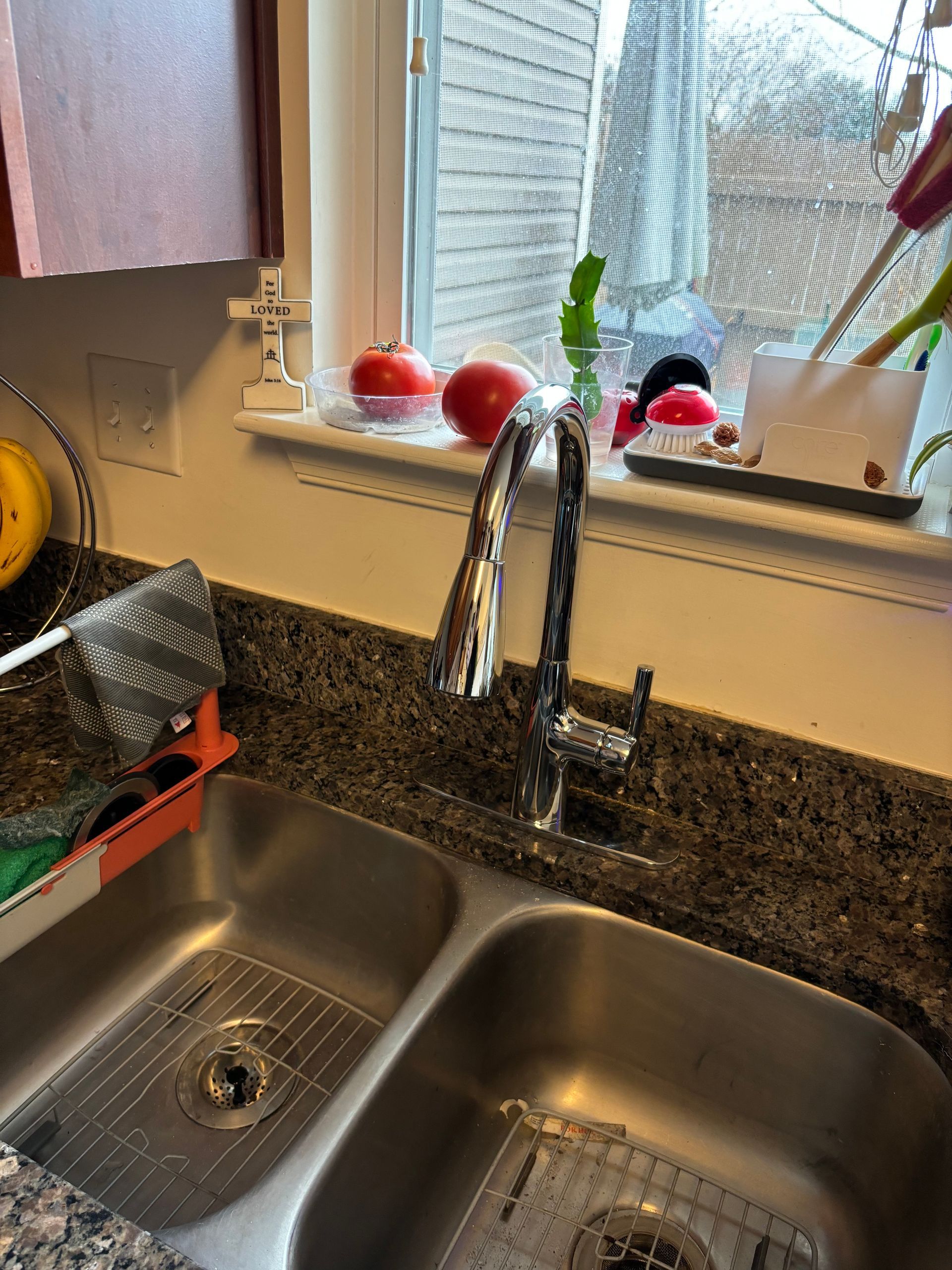 A kitchen sink with a high-arched faucet in front of a window sill. Decorative items sit on the sill.
