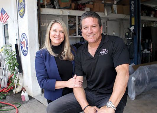A man and a woman are posing for a picture in a garage.