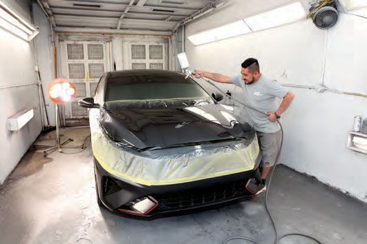 A man is spray painting a car in a garage.