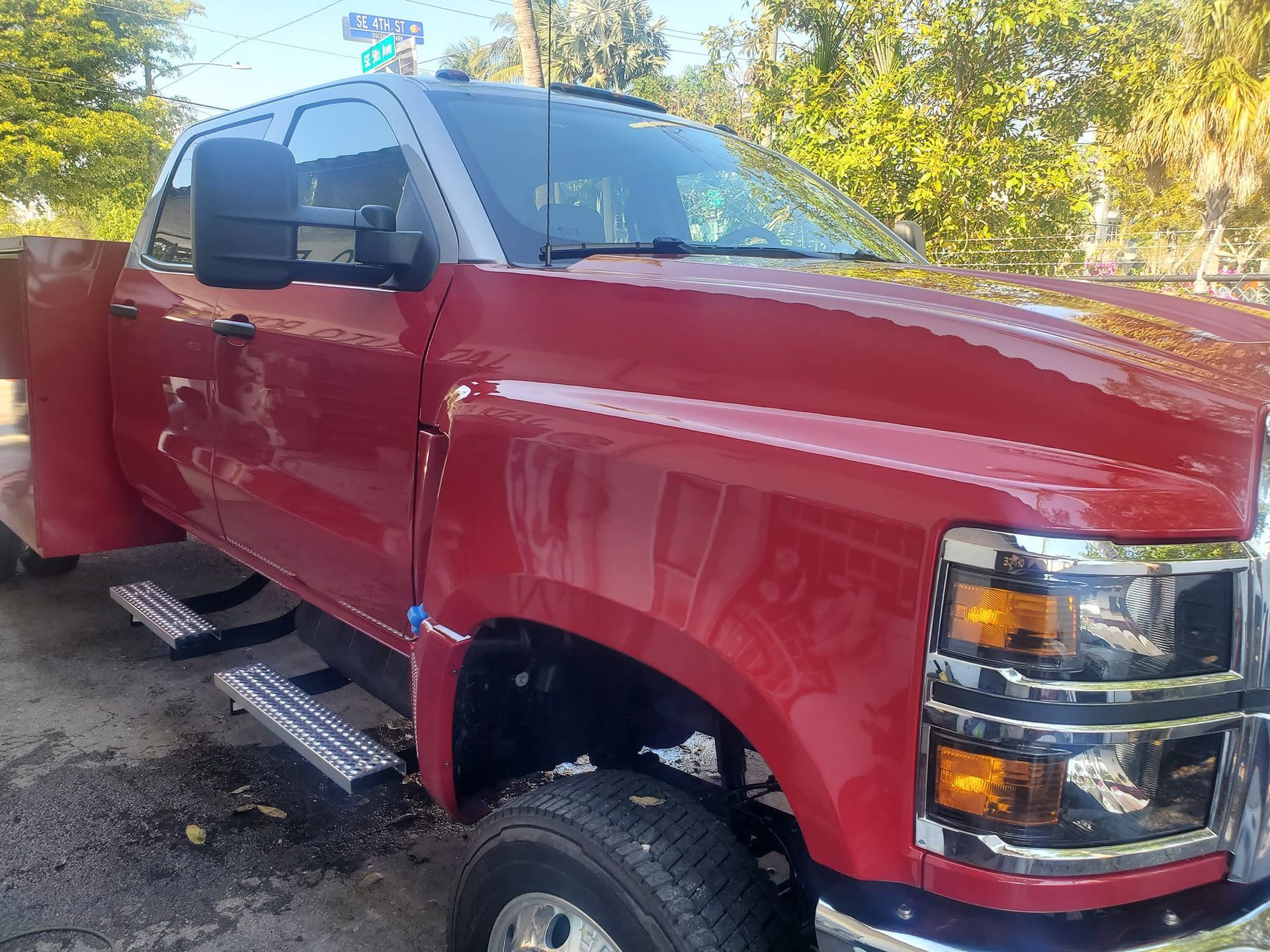 A red truck is parked in a parking lot with trees in the background.