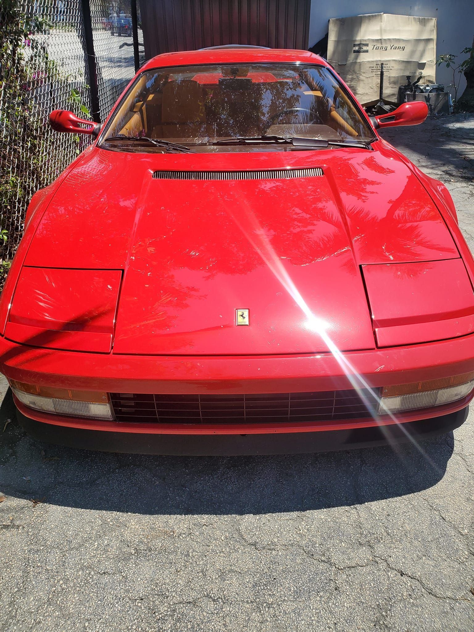 A red ferrari sports car is parked in a driveway.