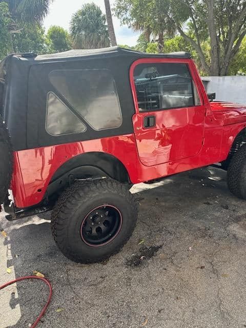 A red jeep is parked on the side of the road