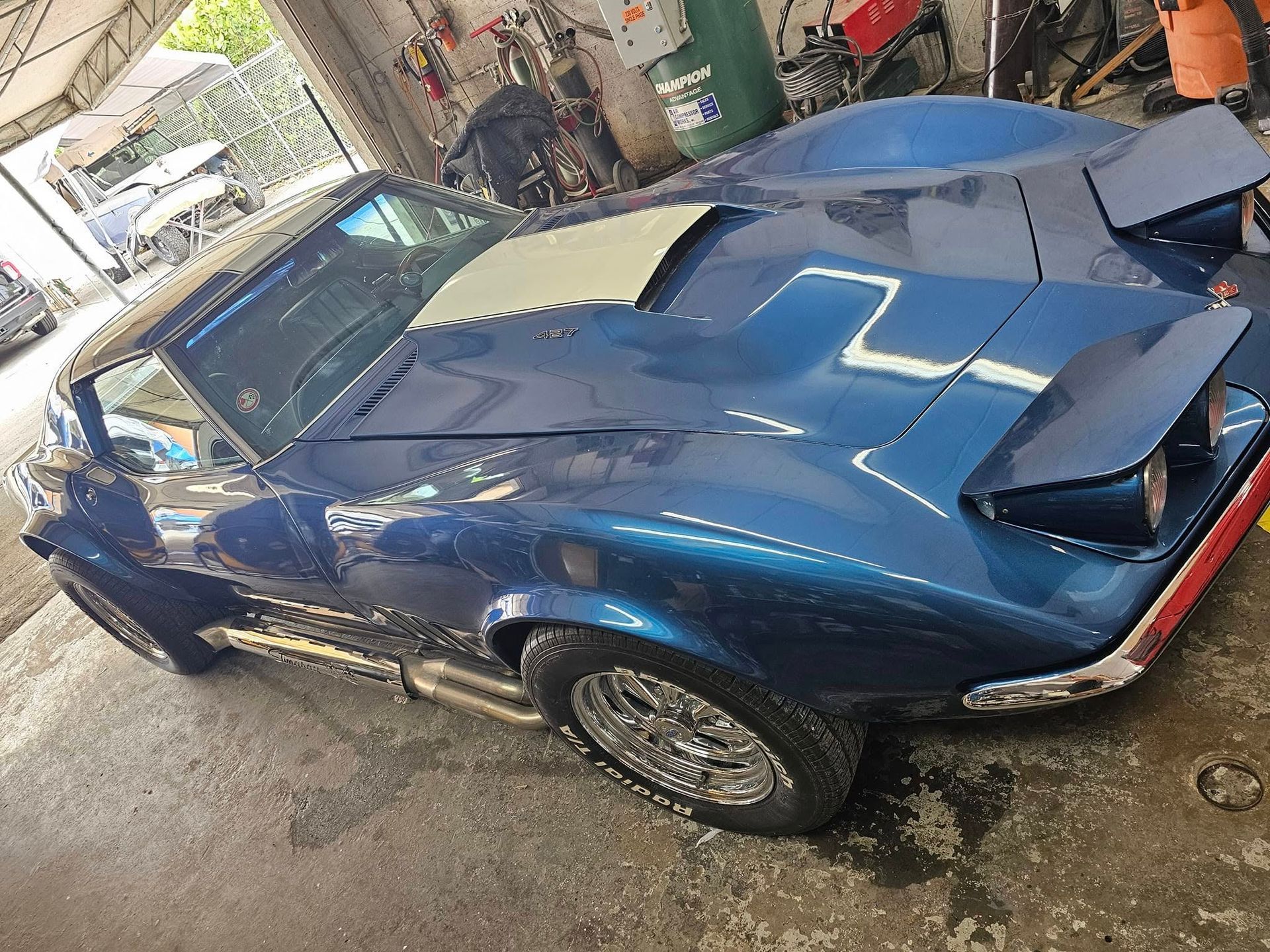 A blue corvette is parked in a garage.