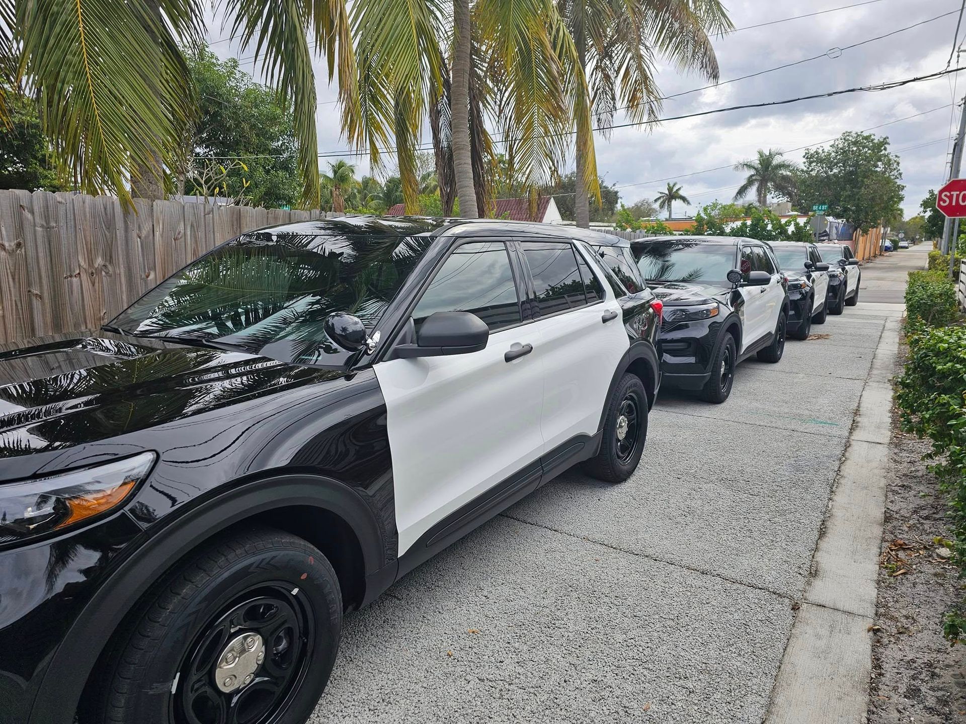 A row of black and white police cars are parked on the side of the road.