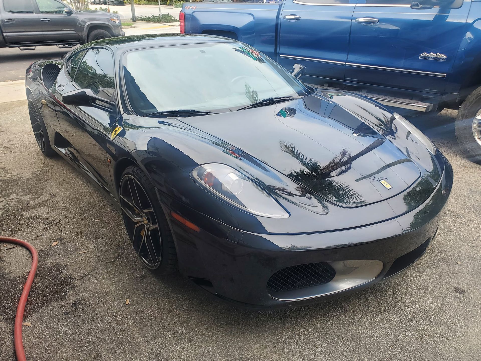 A black sports car is parked next to a blue truck.