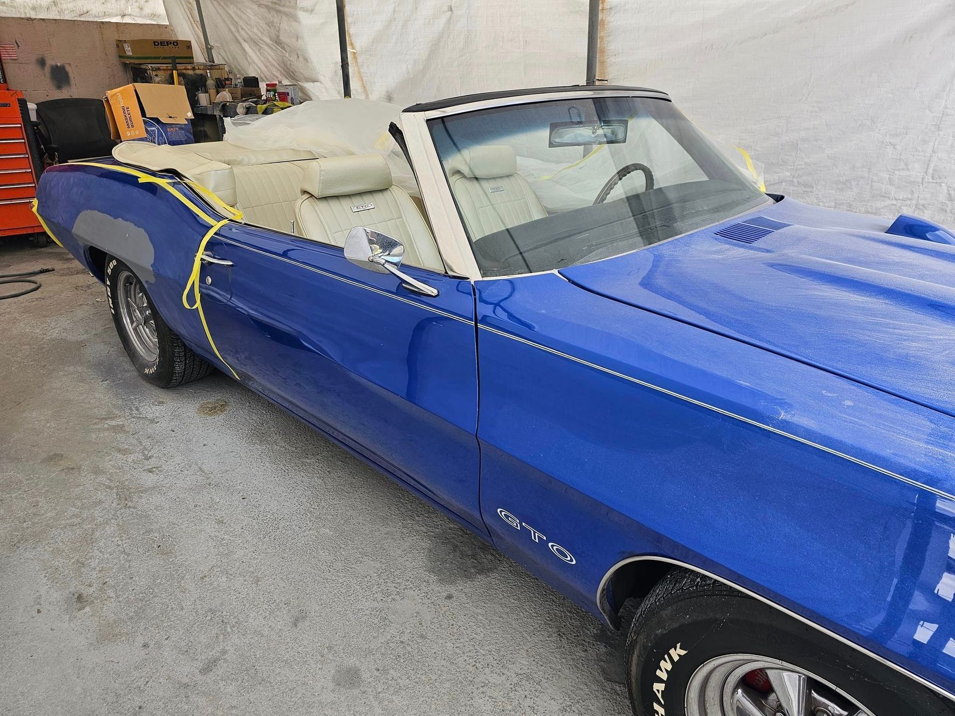 A blue convertible is parked in front of a white tent