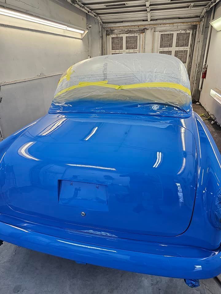A blue car is sitting in a paint booth.