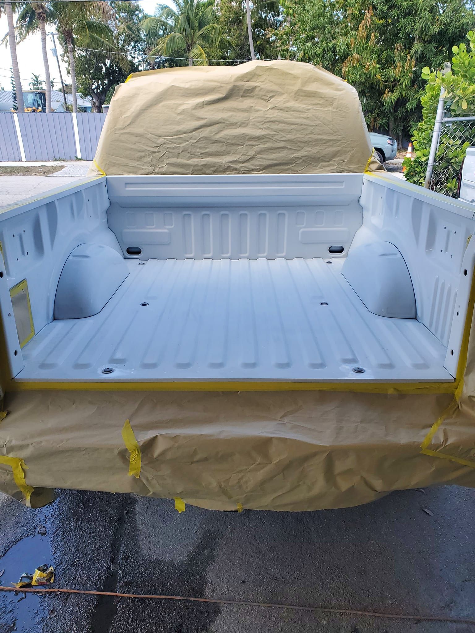 The back of a white truck is being painted.