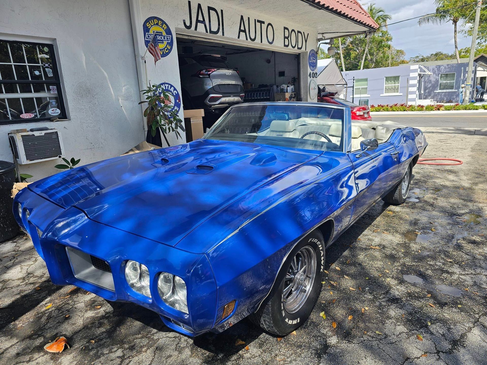 A blue car is parked in front of a garage.