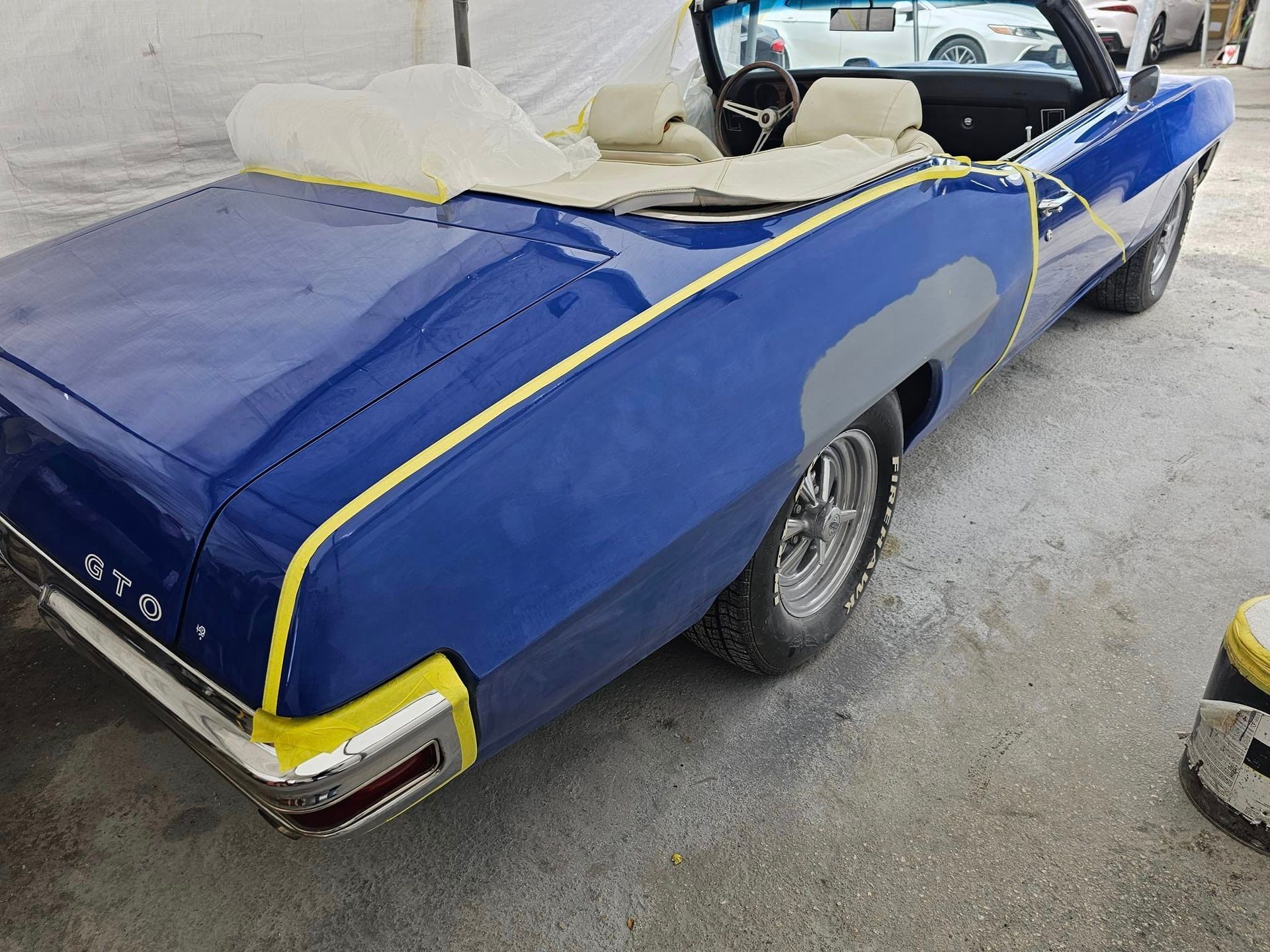 A blue car with a yellow stripe on the side is parked in a parking lot.
