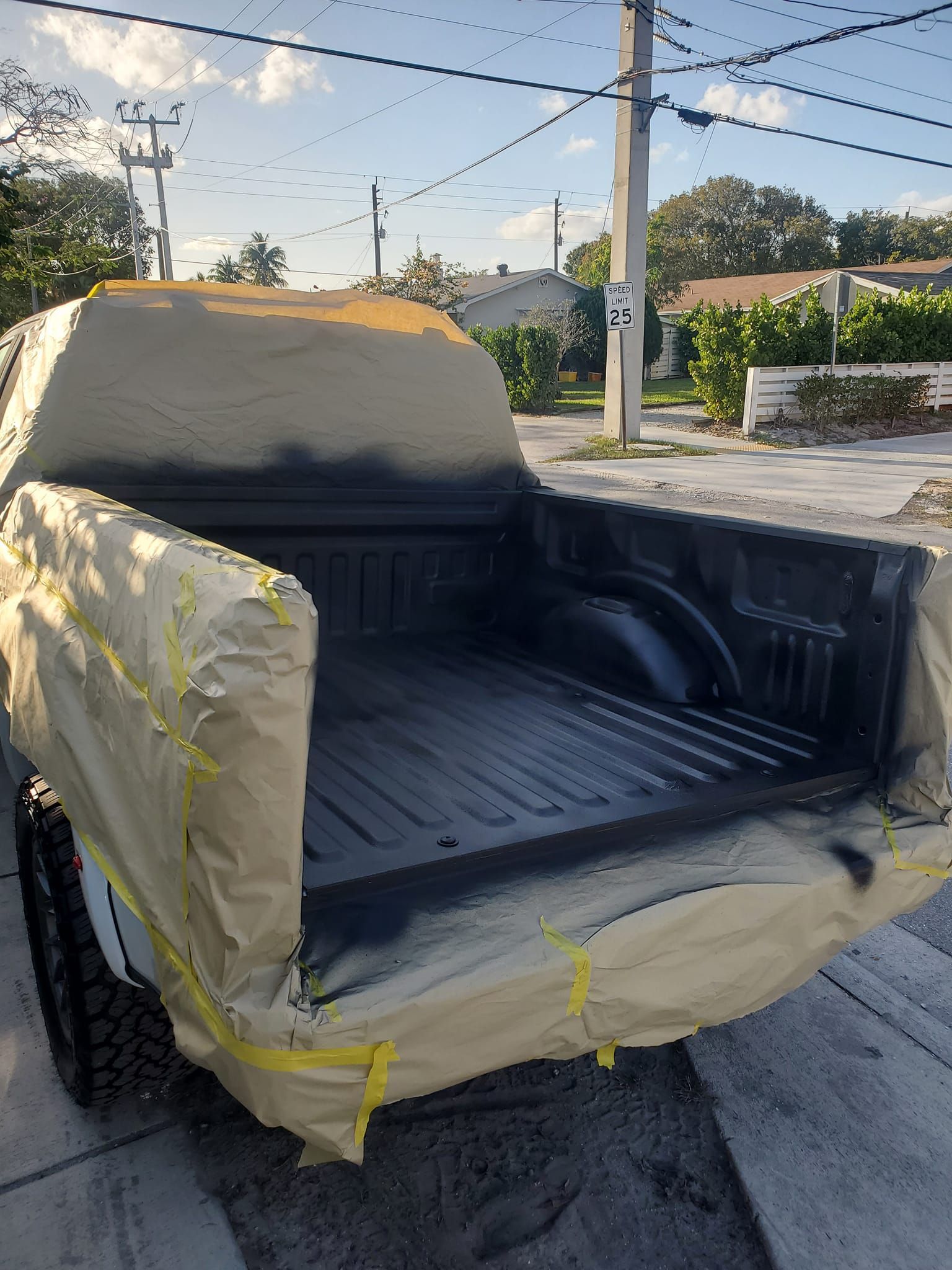 A truck is covered in tape and is sitting on the side of the road.