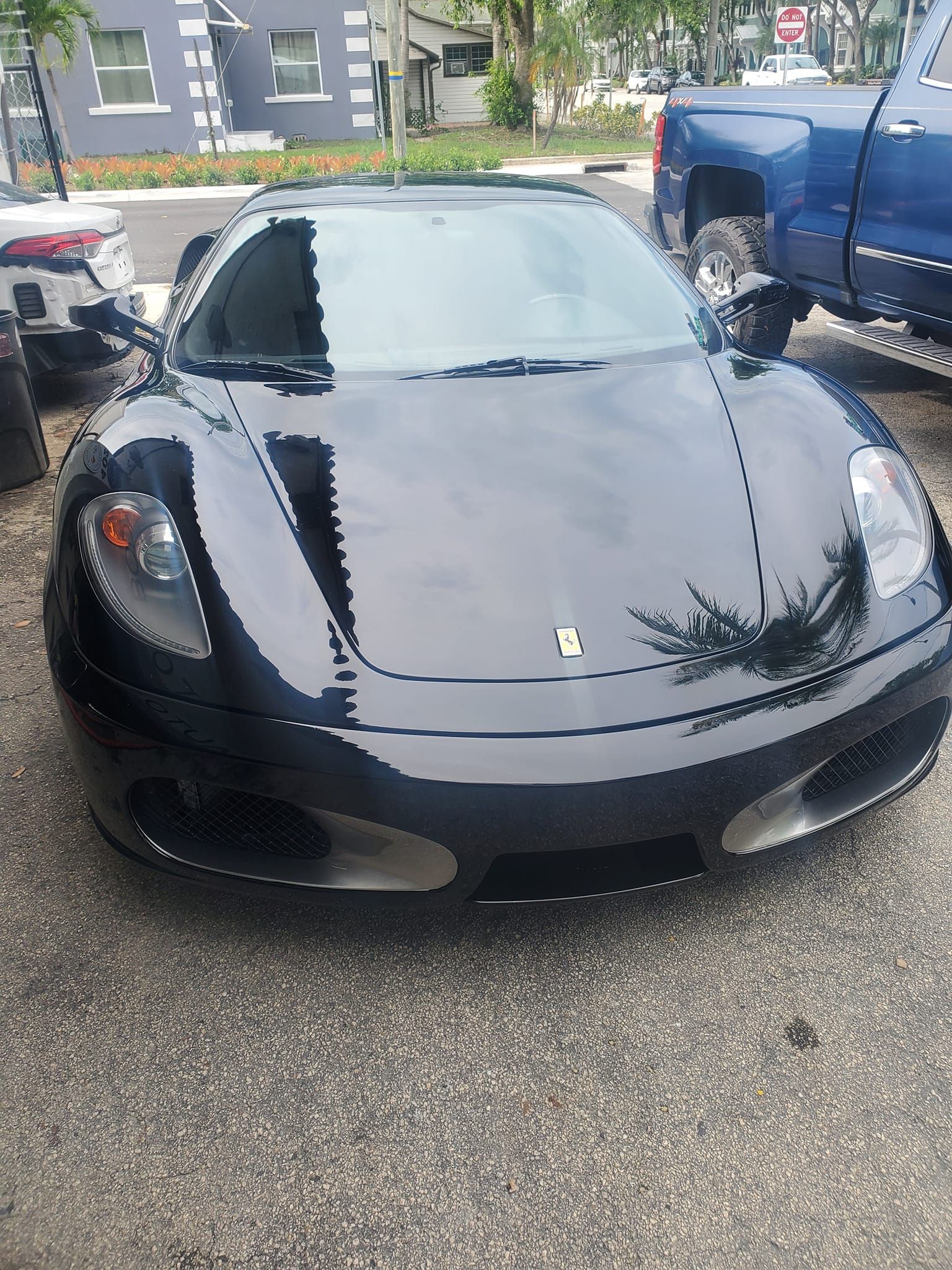 A black sports car is parked next to a blue truck.