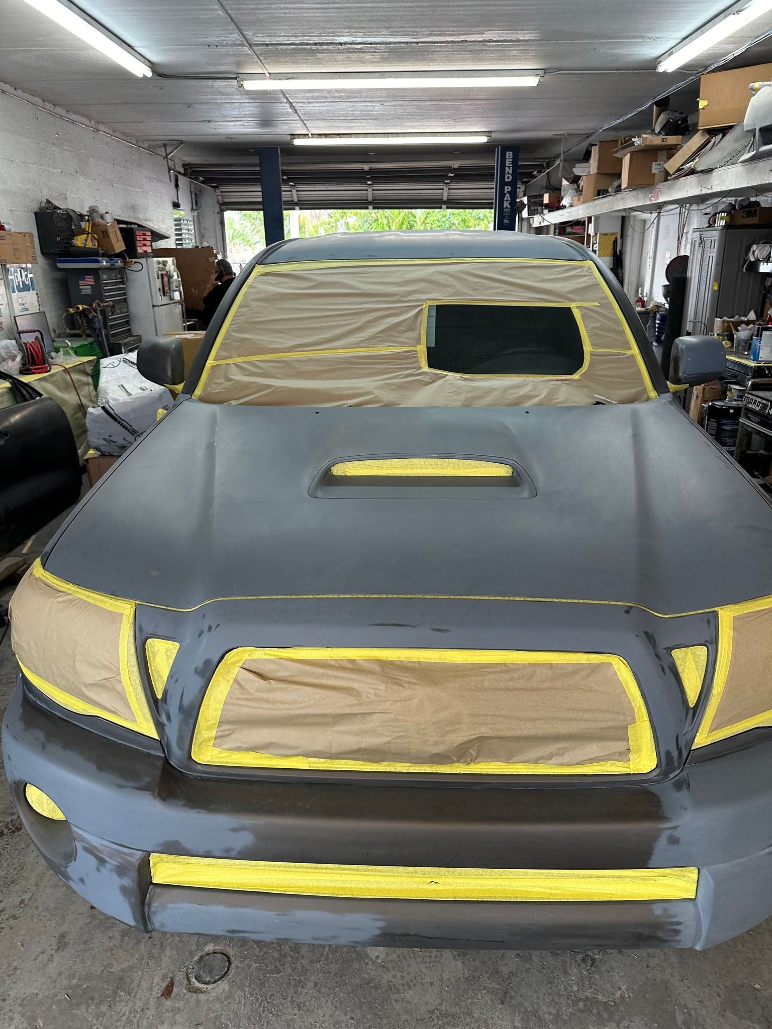 A gray truck is being painted in a garage.