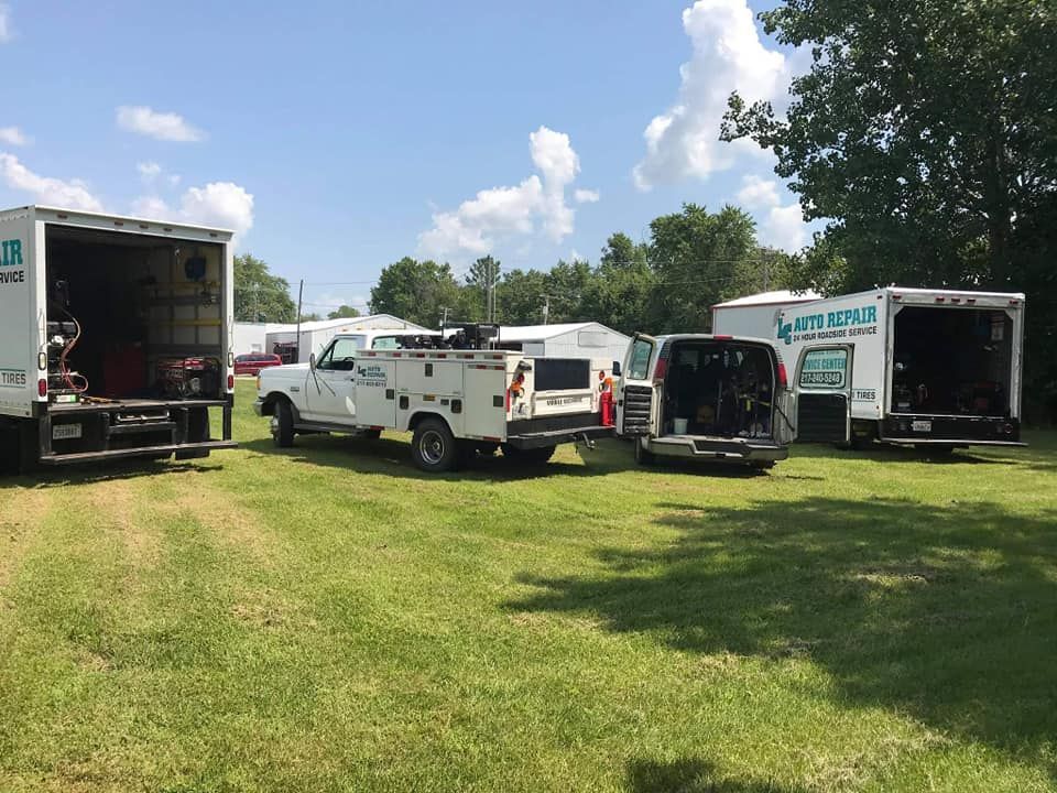Utility trucks parked on a grassy field under a partly cloudy sky.