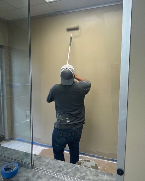 A man is painting a wall with a roller.