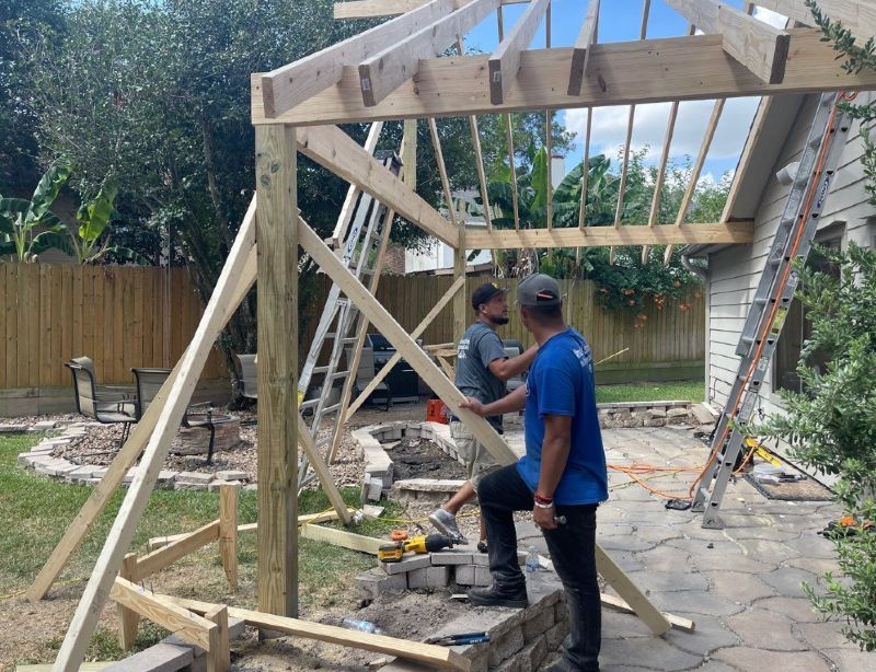 Two men are working on a wooden structure in a backyard.