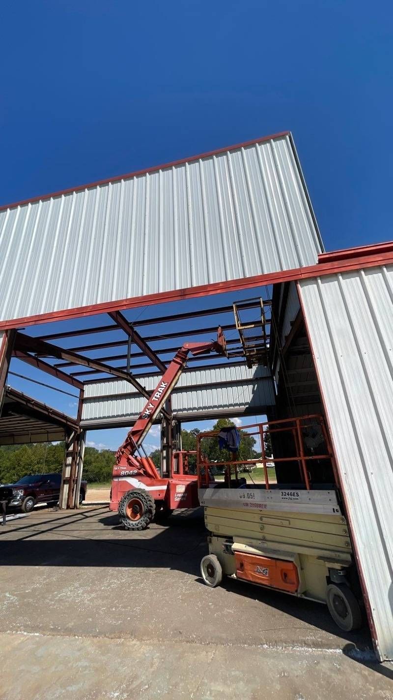 A red crane is sitting in front of a building under construction.