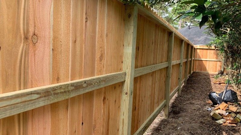 A wooden fence is being built in a backyard.