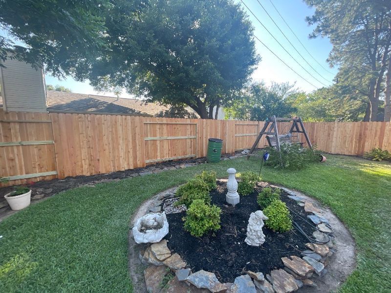 A backyard with a wooden fence and a rock garden.