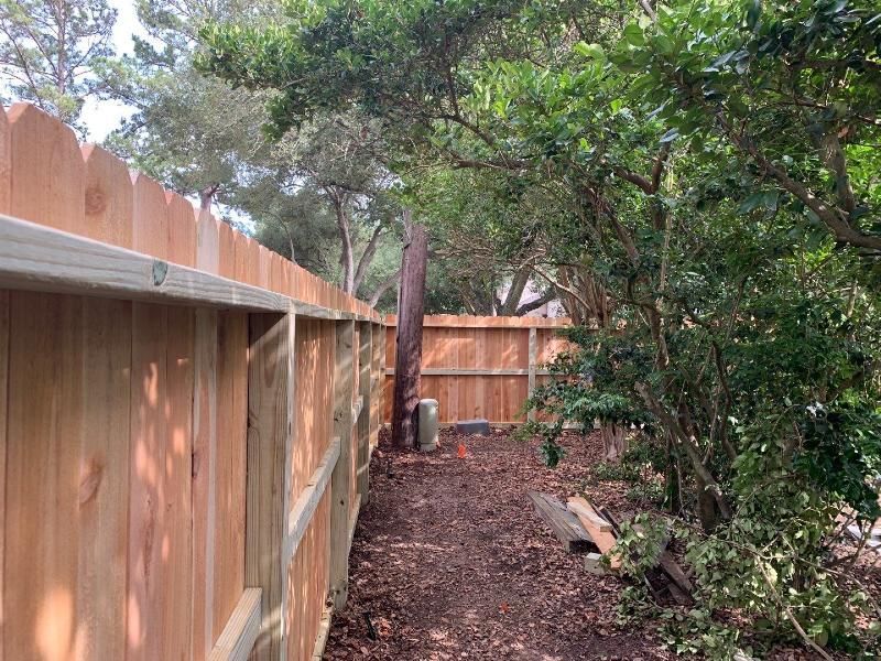 A wooden fence is surrounded by trees and a path.