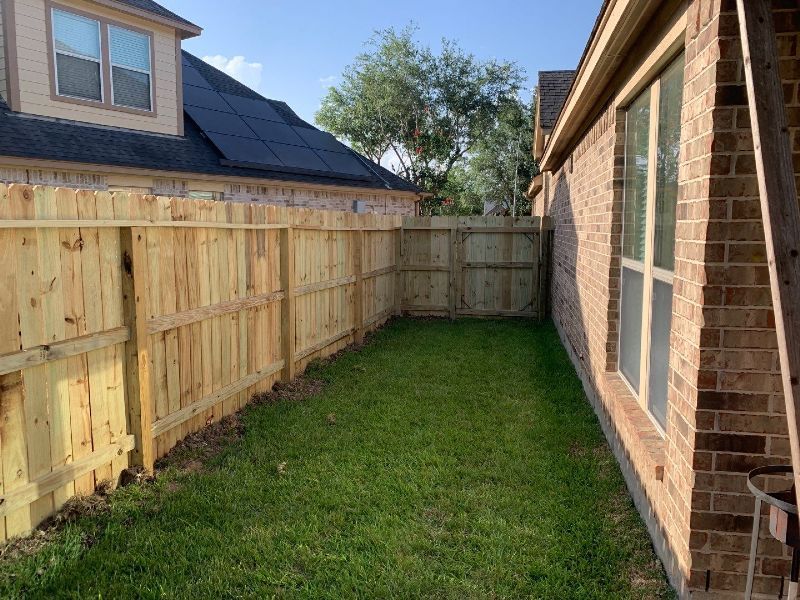 There is a wooden fence in the backyard of a house.