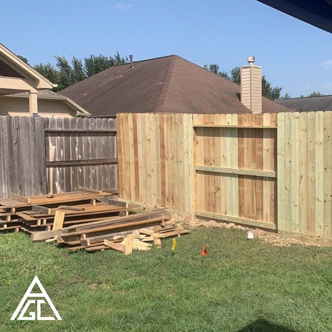A wooden fence is being built in the backyard of a house.