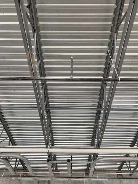 A close up of a metal roof with pipes hanging from it.