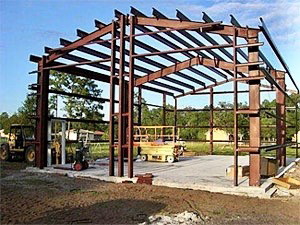 A large metal structure is being built with a tractor in the background.