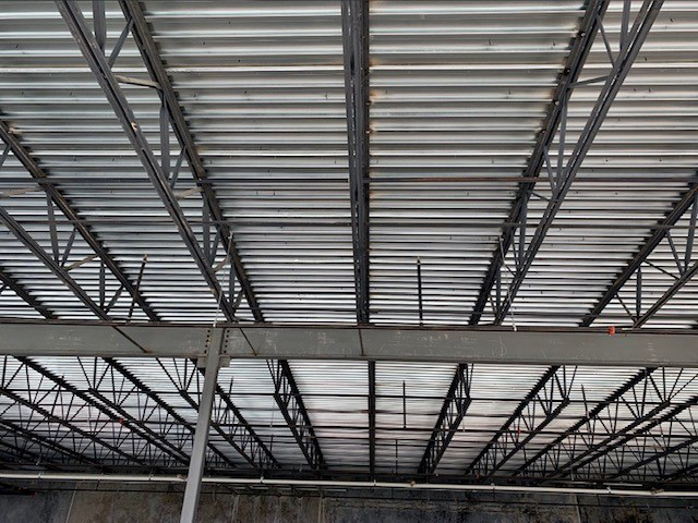The ceiling of a building under construction is made of metal.