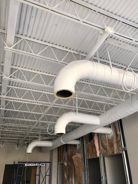 A ceiling with a lot of white pipes hanging from it