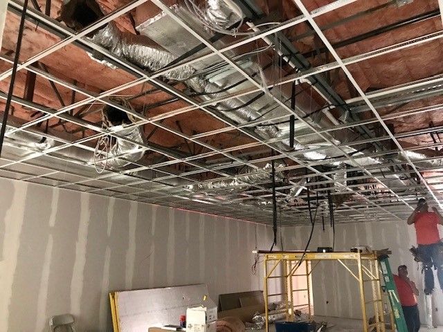 A man is working on the ceiling of a building.