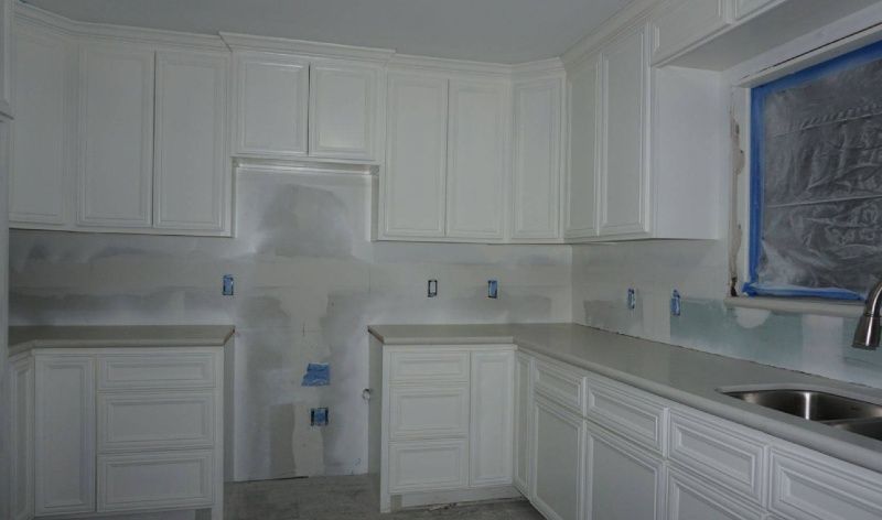 A kitchen with white cabinets and a stainless steel sink.