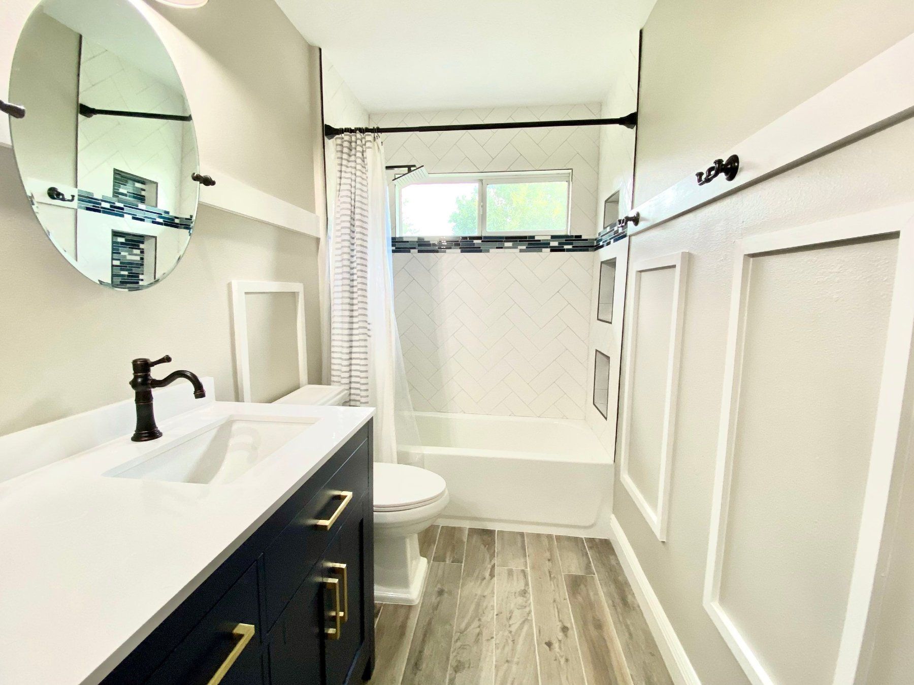 A bathroom with a sink , toilet , shower and mirror.