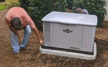 A man is working on a generator in the dirt.