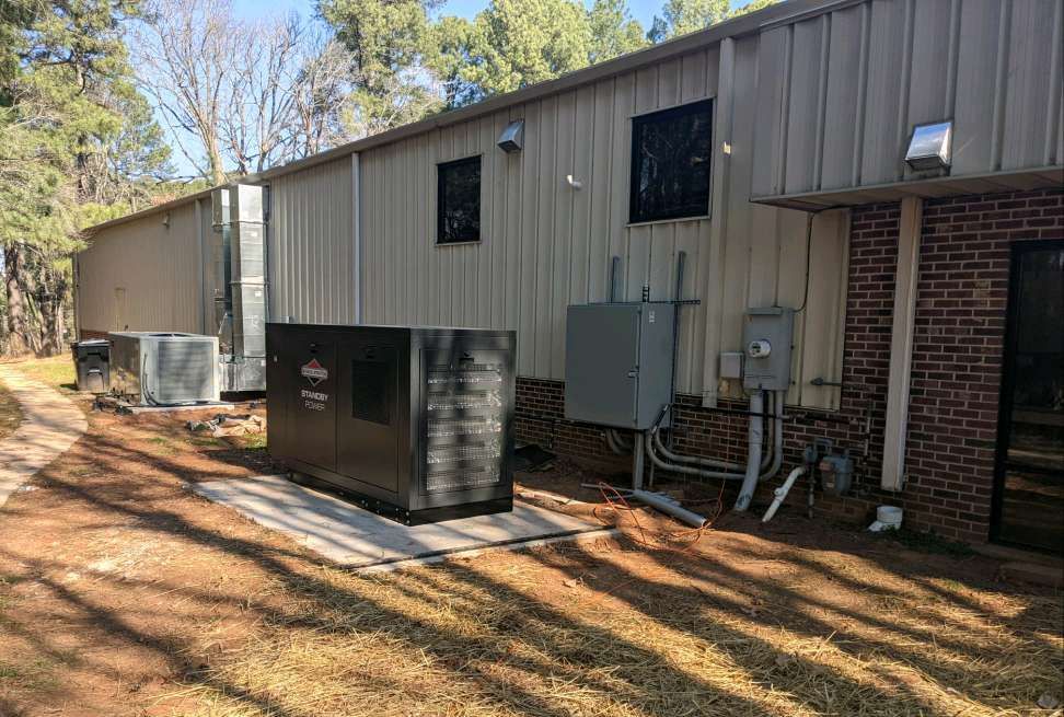 A large building with a lot of electrical equipment and generator on the side of it.