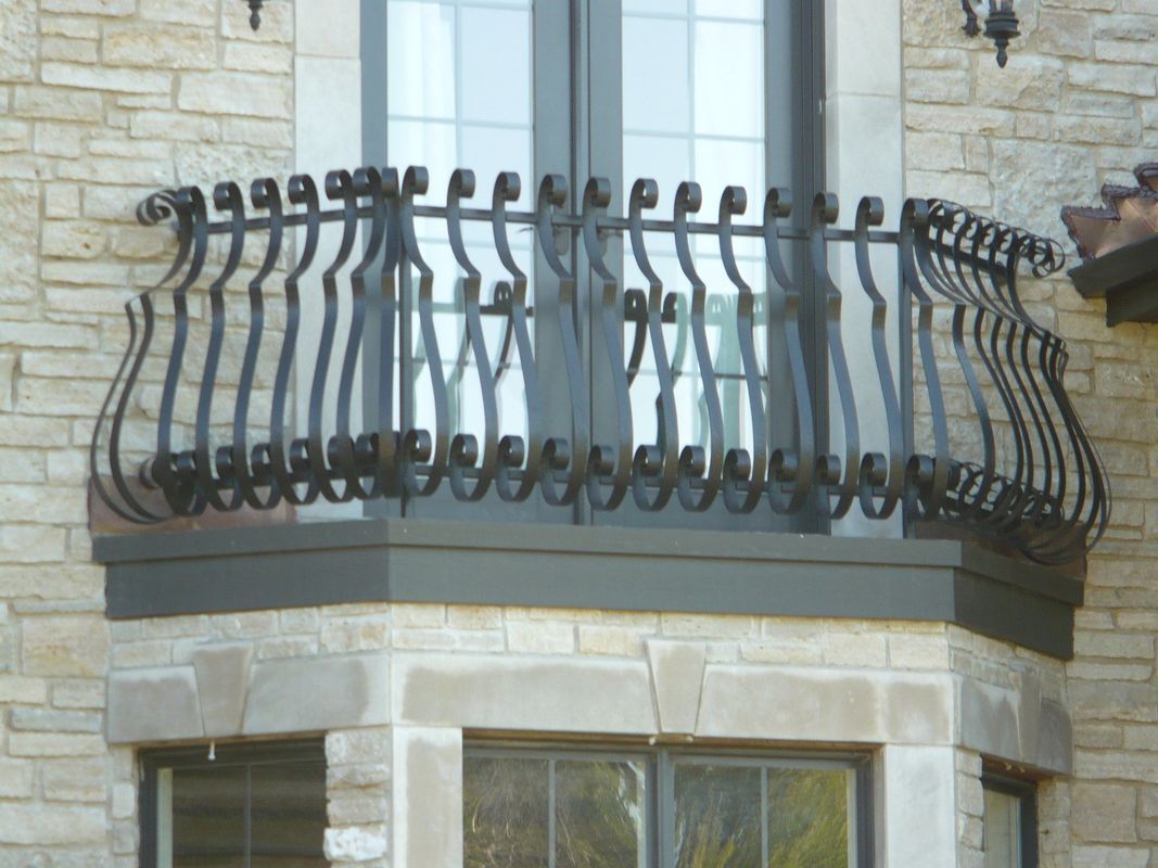 A balcony with a wrought iron railing on a brick building