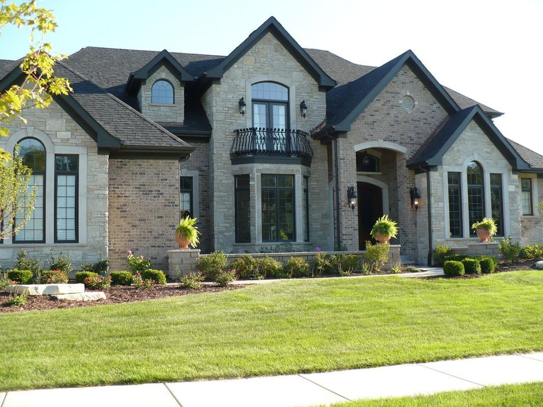 A large brick house with a balcony and a lush green lawn
