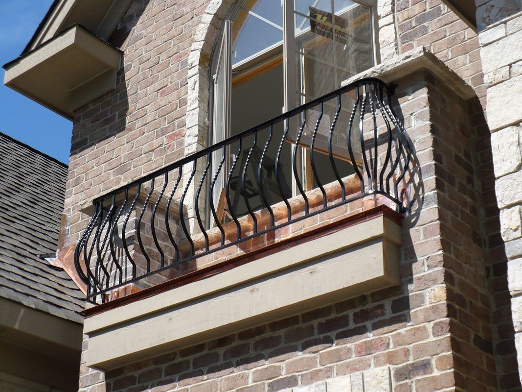 A brick building with a balcony with a wrought iron railing