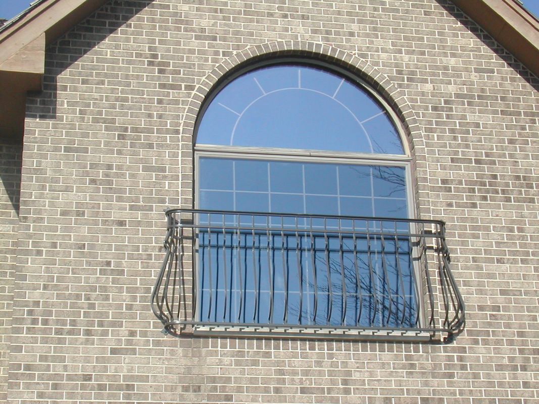 A brick building with an arched window and a balcony