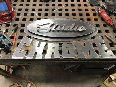 A metal sign that says studio chrome is sitting on top of a metal table.